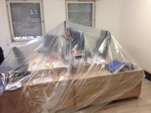 Mit Plastikfolie abgedeckte Schreibtische vor neuen Fenstern